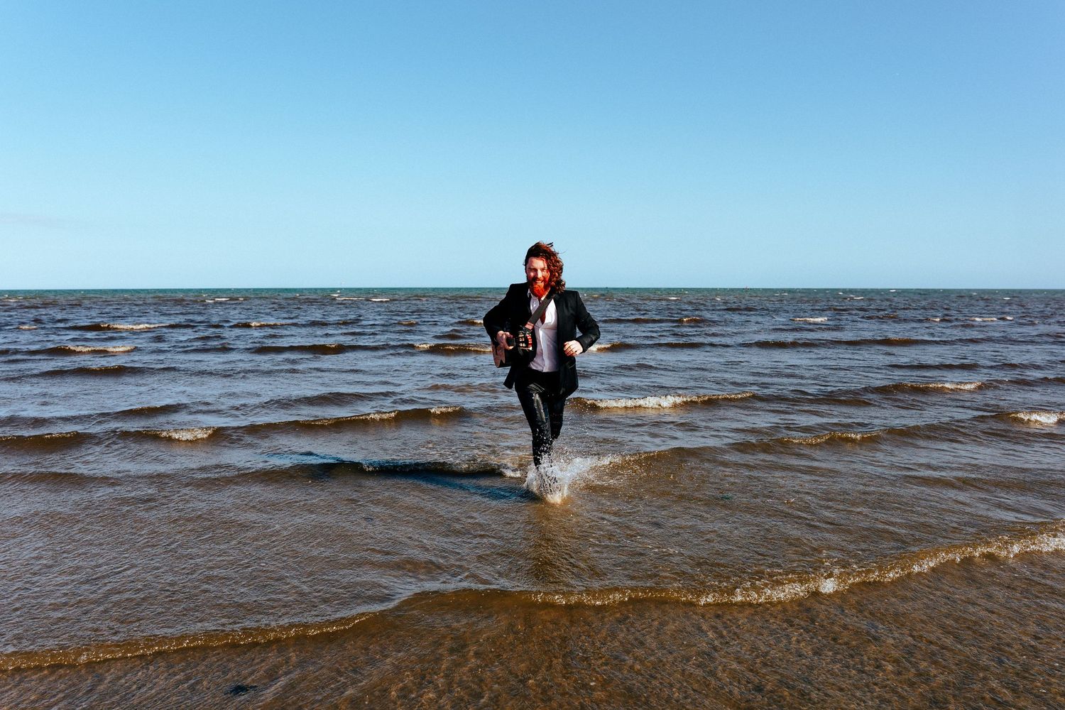 A person joyfully splashes through shallow coastal waters on a sunny day at the beach. PHOTOGRAPHER Dublin