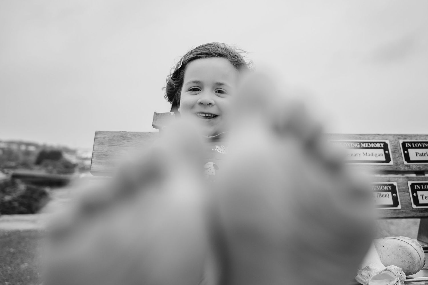 Black and white closeup of bare feet in focus with a blurred smiling figure in the background. PHOTOGRAPHER Dublin