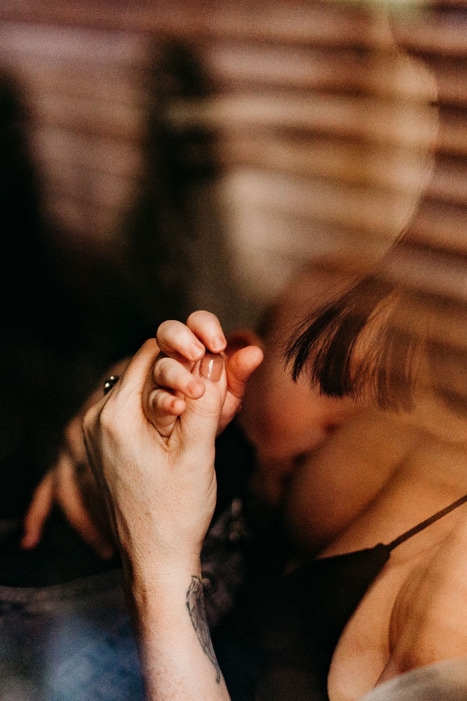 An intimate moment captured with clasped hands and shadows in warm lighting.  Family PHOTOGRAPHER Dublin