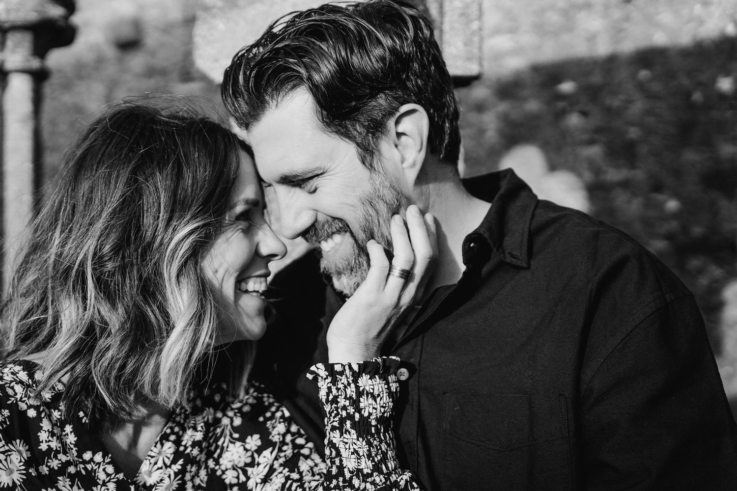 Black and white romantic portrait of a joyful couple sharing an intimate laugh together outdoors. Photographer Ireland dublin