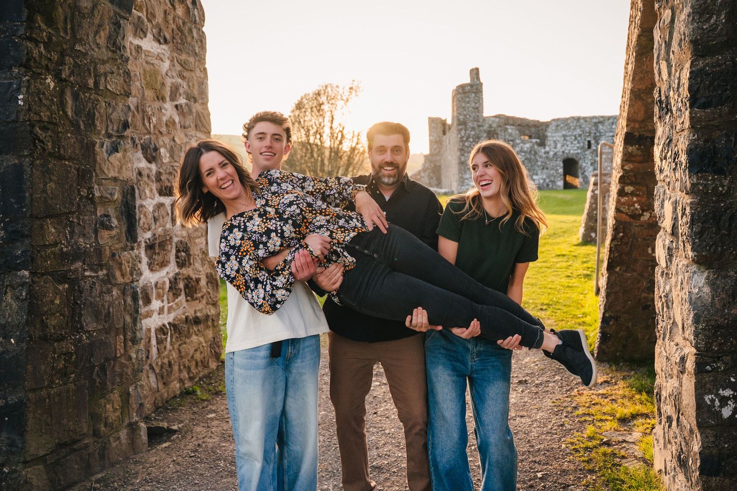 Joyful couple poses playfully between stone archways of medieval castle ruins. Photographer Ireland dublin