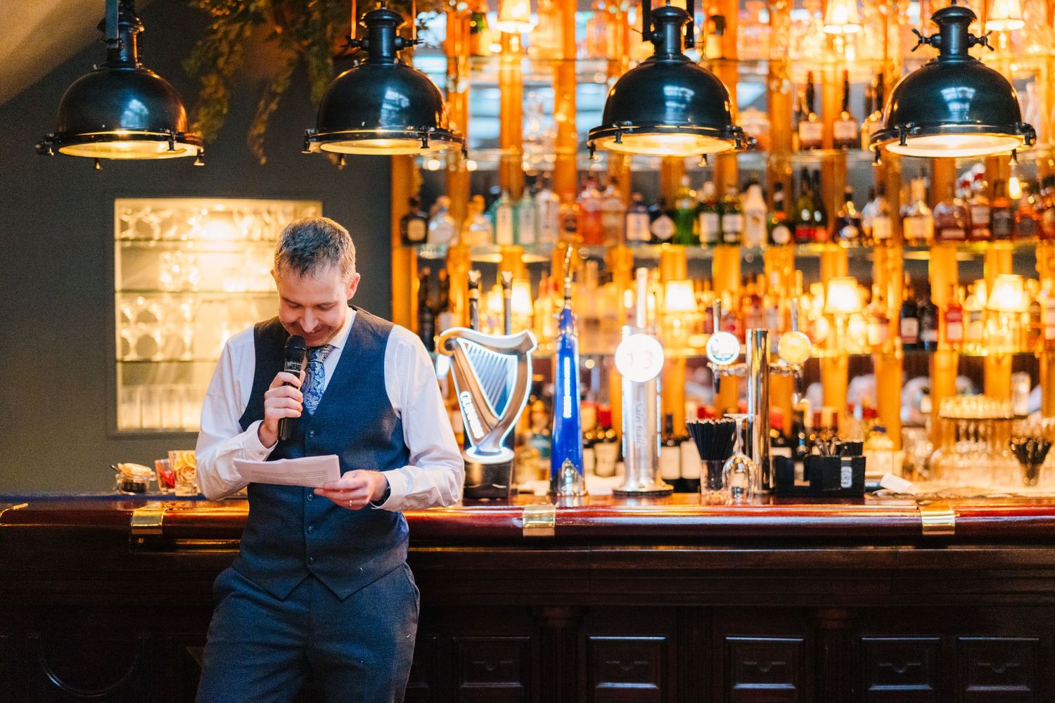 Guests enjoying drinks and conversation at a warmly lit bar with pendant lighting and wood finishes. Marco Pierre Dublin Wedding Photographe