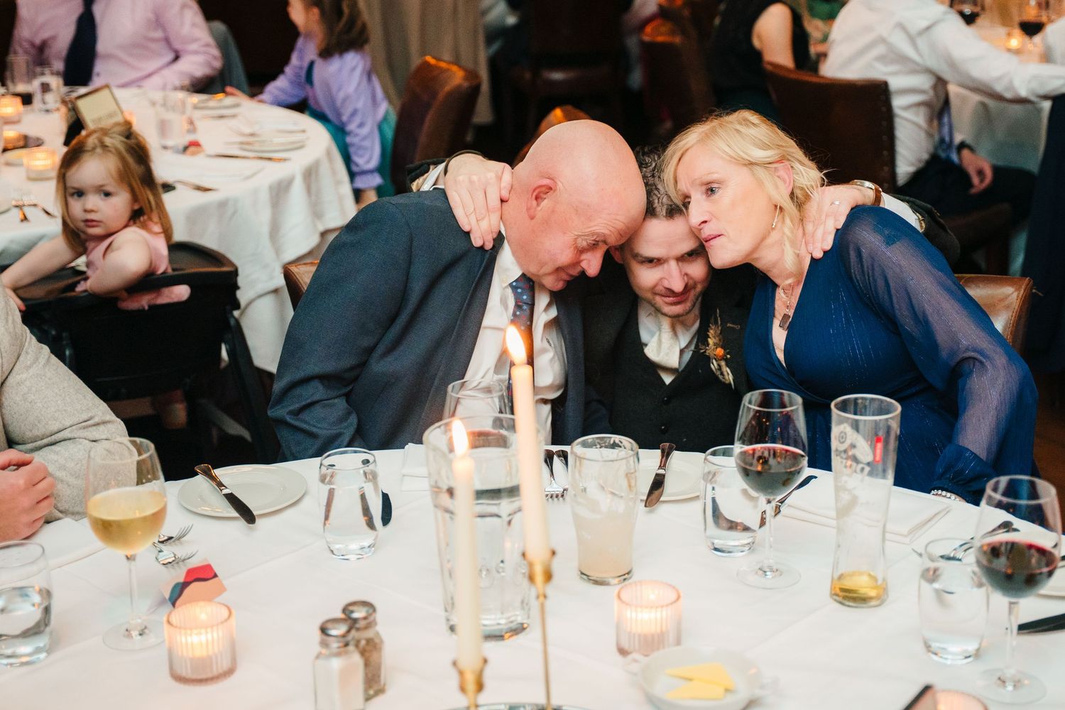 Wedding guests share an intimate moment at an elegant dinner reception with candlelit tables and wine glasses. Marco Pierre Dublin Wedding P