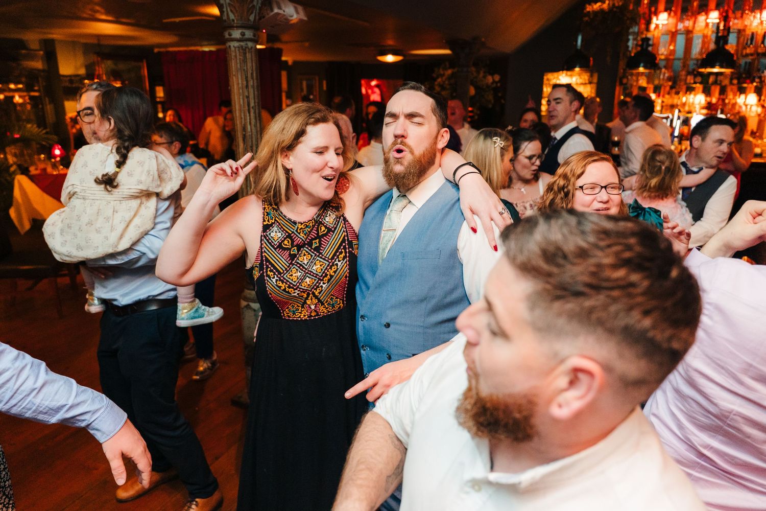 Party guests dance and sing energetically on a crowded dance floor at a dimly lit event venue. Marco Pierre Dublin Wedding Photographer