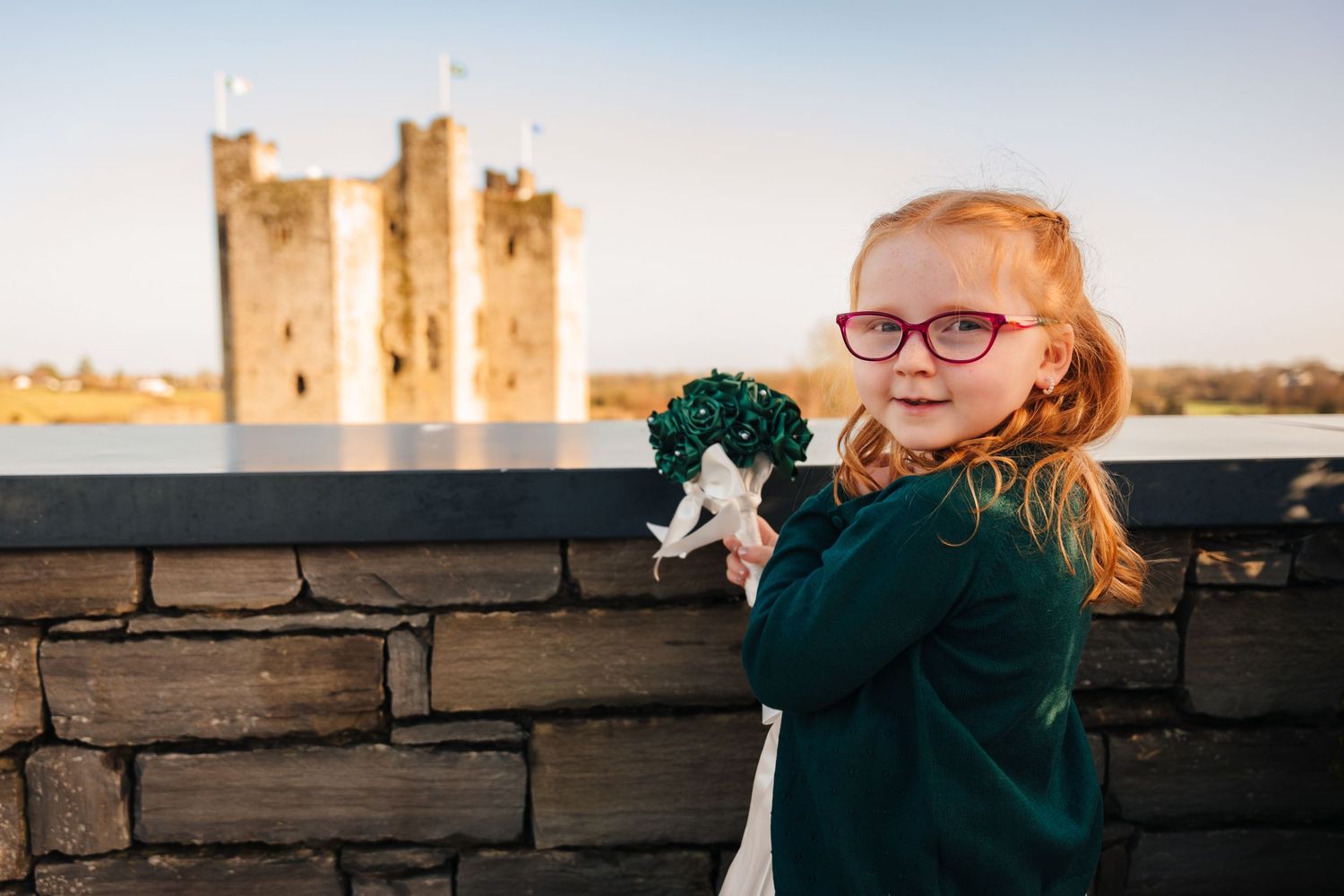 Wedding party posing against stone walls during golden hour with castle towers in background.  Wedding PHOTOGRAPHER Trim Castle