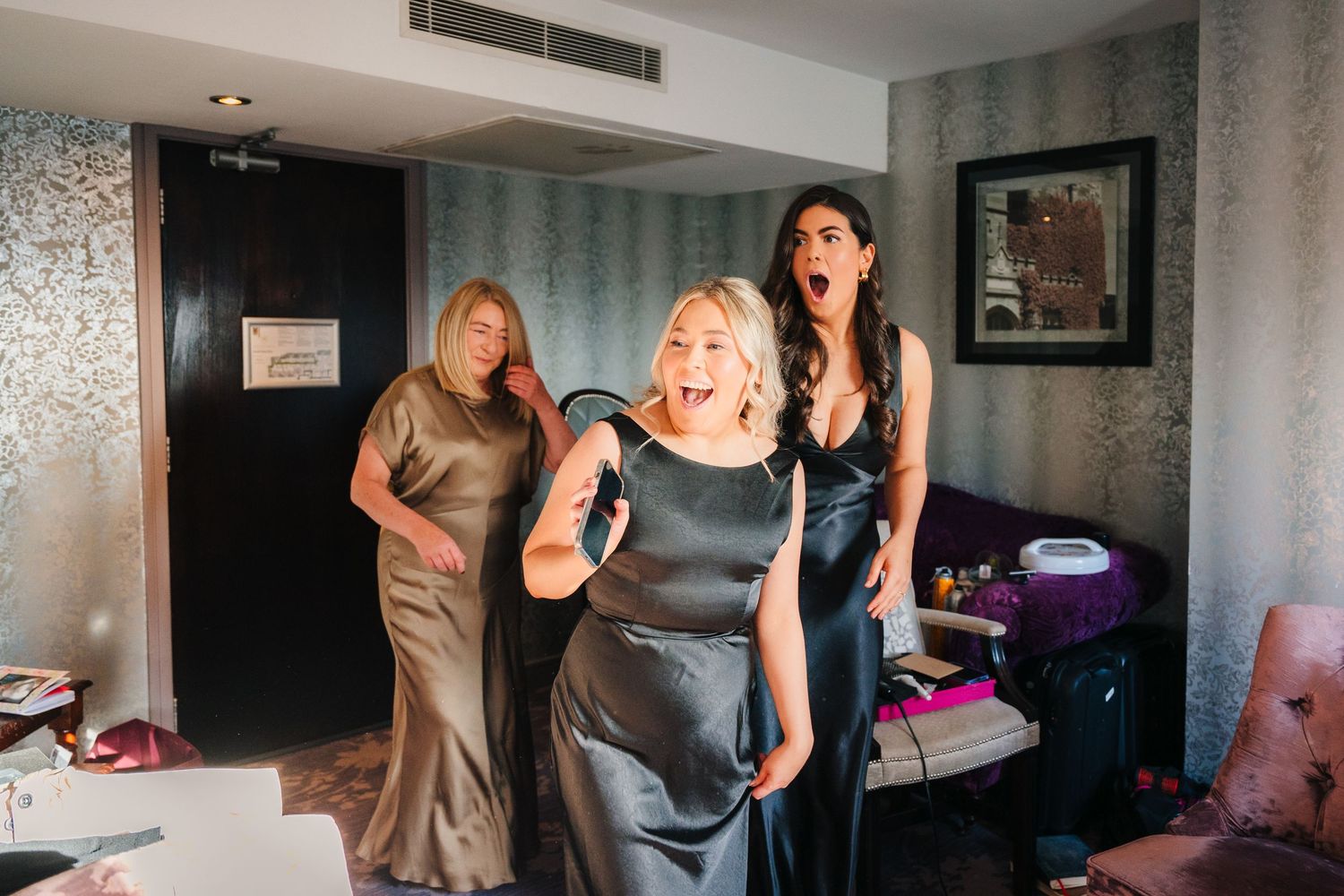 Three people in elegant dresses stand in a room during what appears to be a formal event preparation. City Hall Dublin Photographer