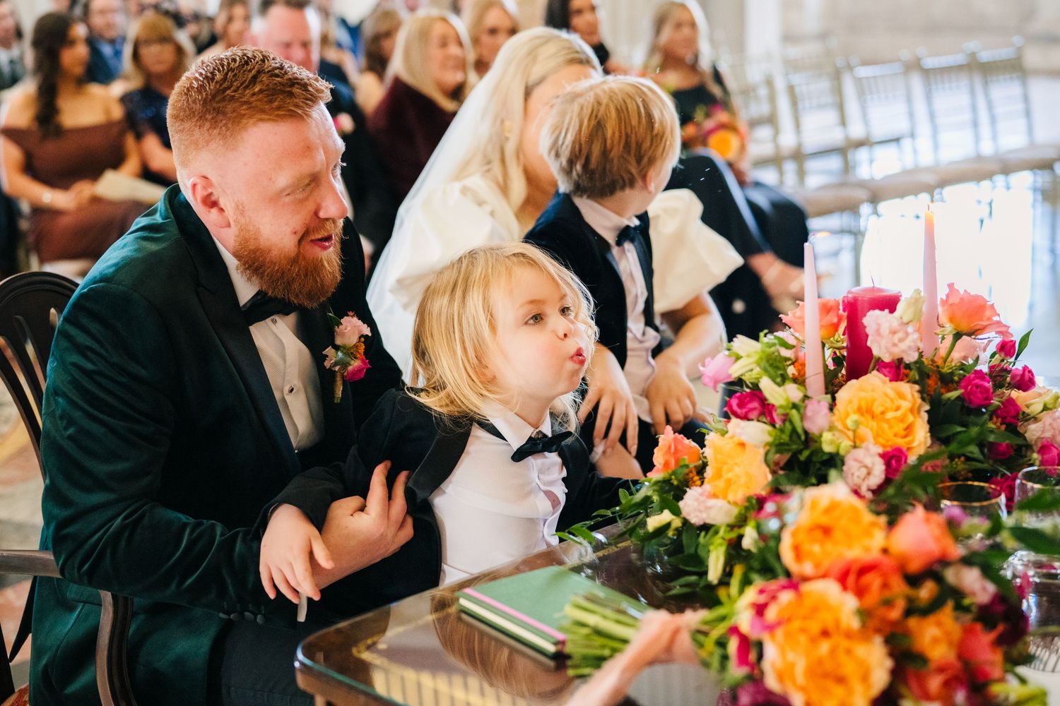 A formal dining table decorated with vibrant orange and pink floral arrangements at a wedding reception. City Hall Dublin Photographer