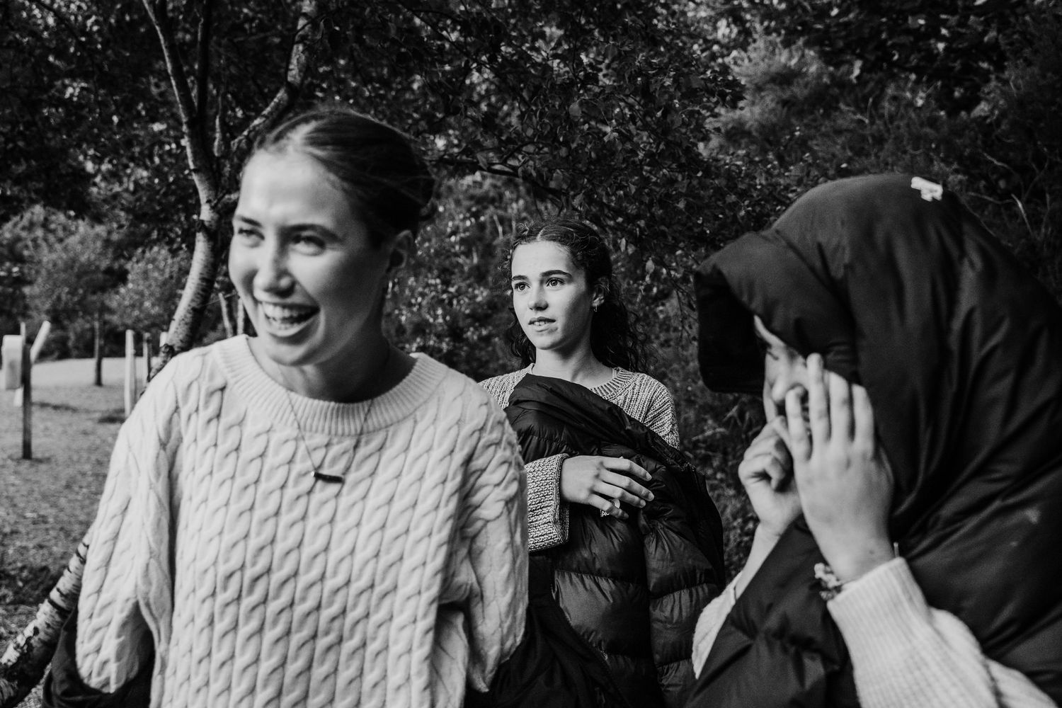 Family photographer Ireland Dublin Black and white candid photo showing three people laughing together in an outdoor setting.