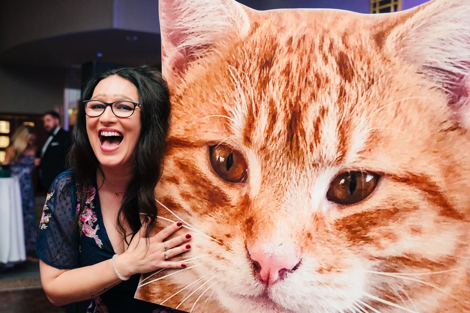 Woman laughing next to large orange tabby cat photo display at event.Wedding Photography Trim Castle Ireland