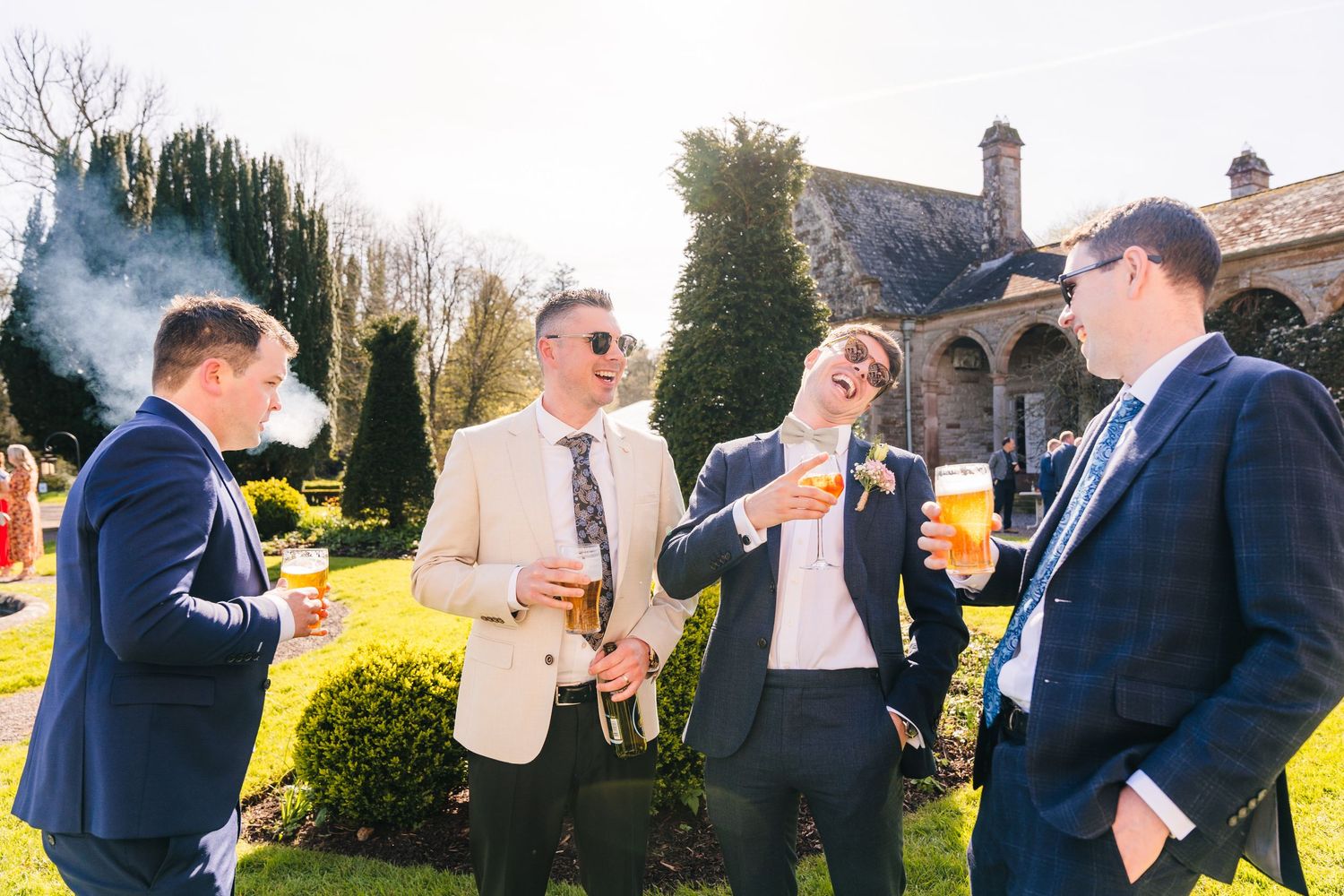 Castle Leslie Wedding Photographer Dublin Well-dressed guests enjoying drinks and conversation in the garden of an elegant stone venue.