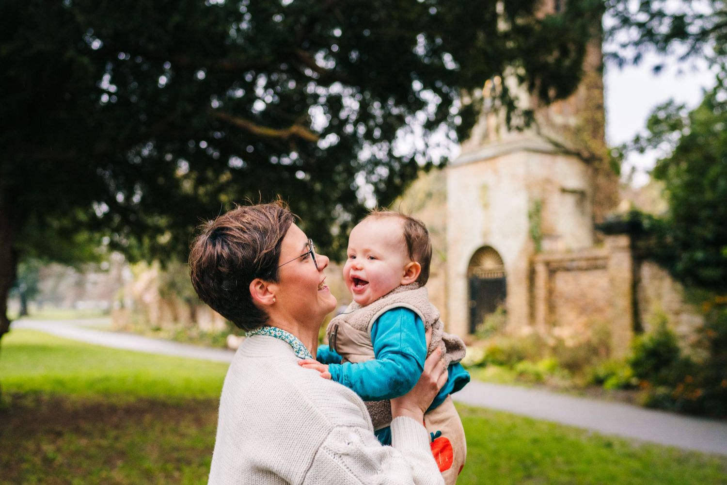 A joyful moment shared between two people laughing together in front of a historic stone church on a sunny day. Family photographer Dublin I