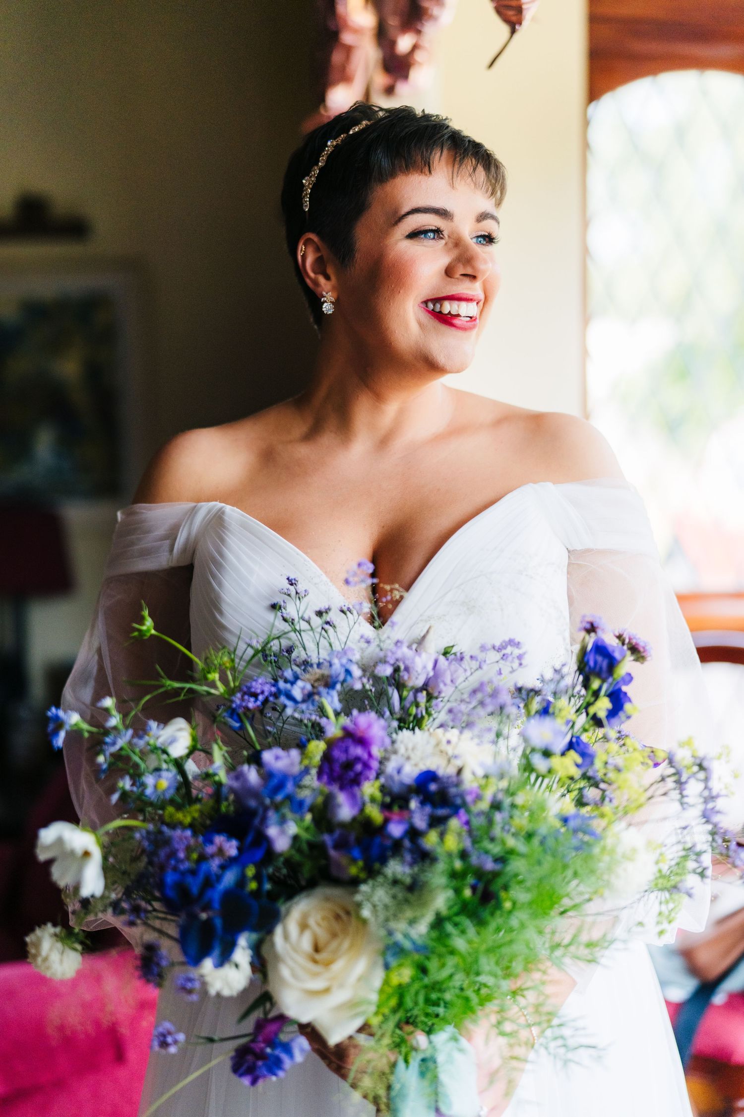 A beautiful wedding bouquet featuring blue delphinium, purple flowers and white roses against a white dress. Millhouse slane wedding photogr