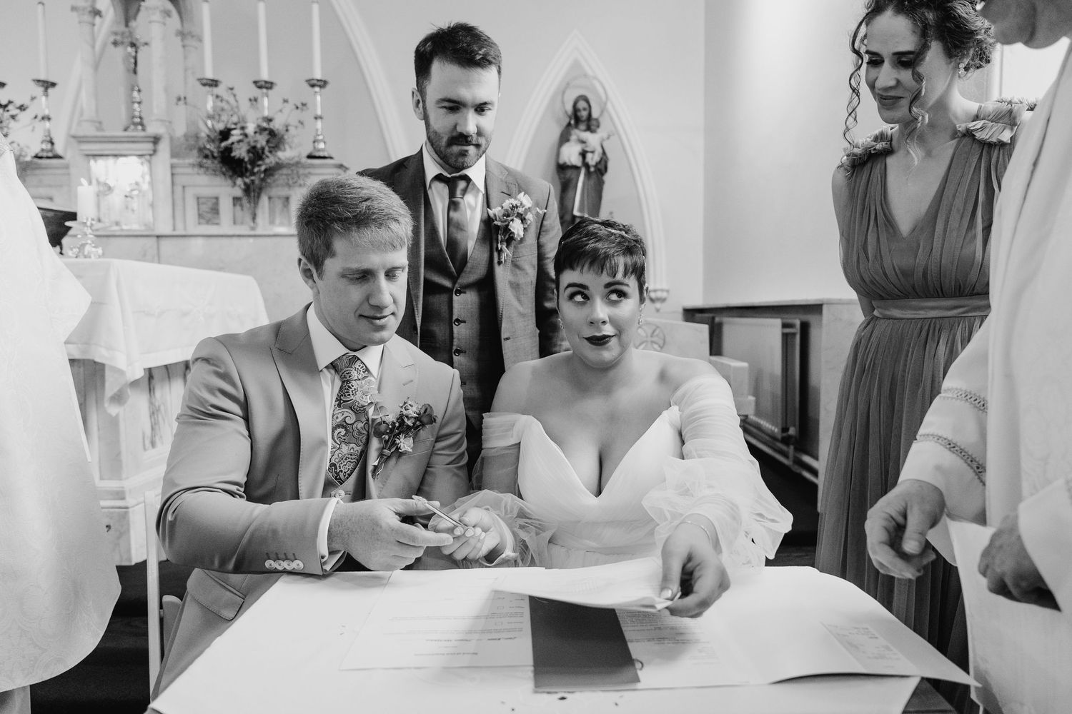 Millhouse slane wedding photographer dublin Black and white photo of a ceremony where people sign documents at a table with candles.