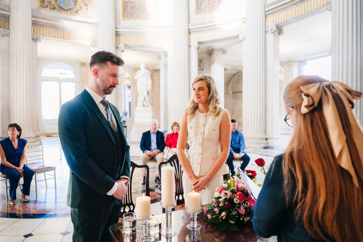 An intimate wedding ceremony taking place in a grand historic room with white columns and ornate details. City Hall Dublin wedding photogrAP