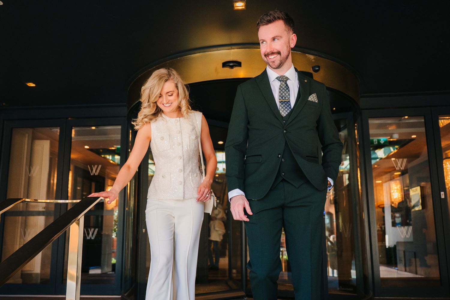 A joyful couple shares a candid moment while walking indoors at night. City Hall Dublin wedding photogrAPher
