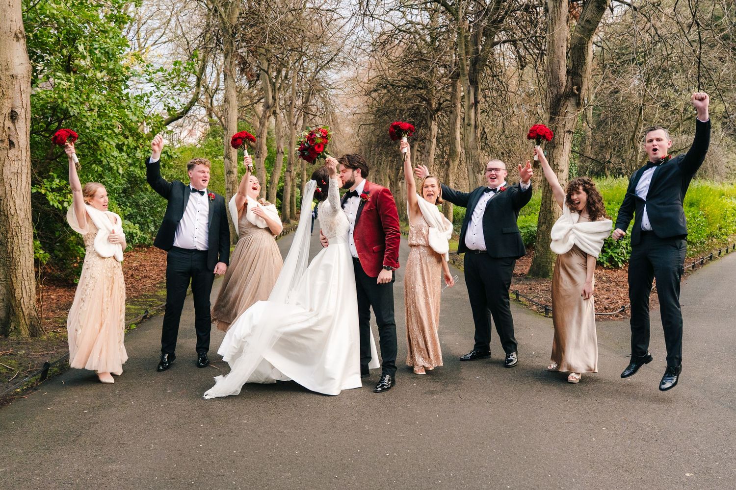 Wedding party poses outdoors in a line against a natural backdrop with trees and stone walls. Stephens green club dublin Wedding photographe