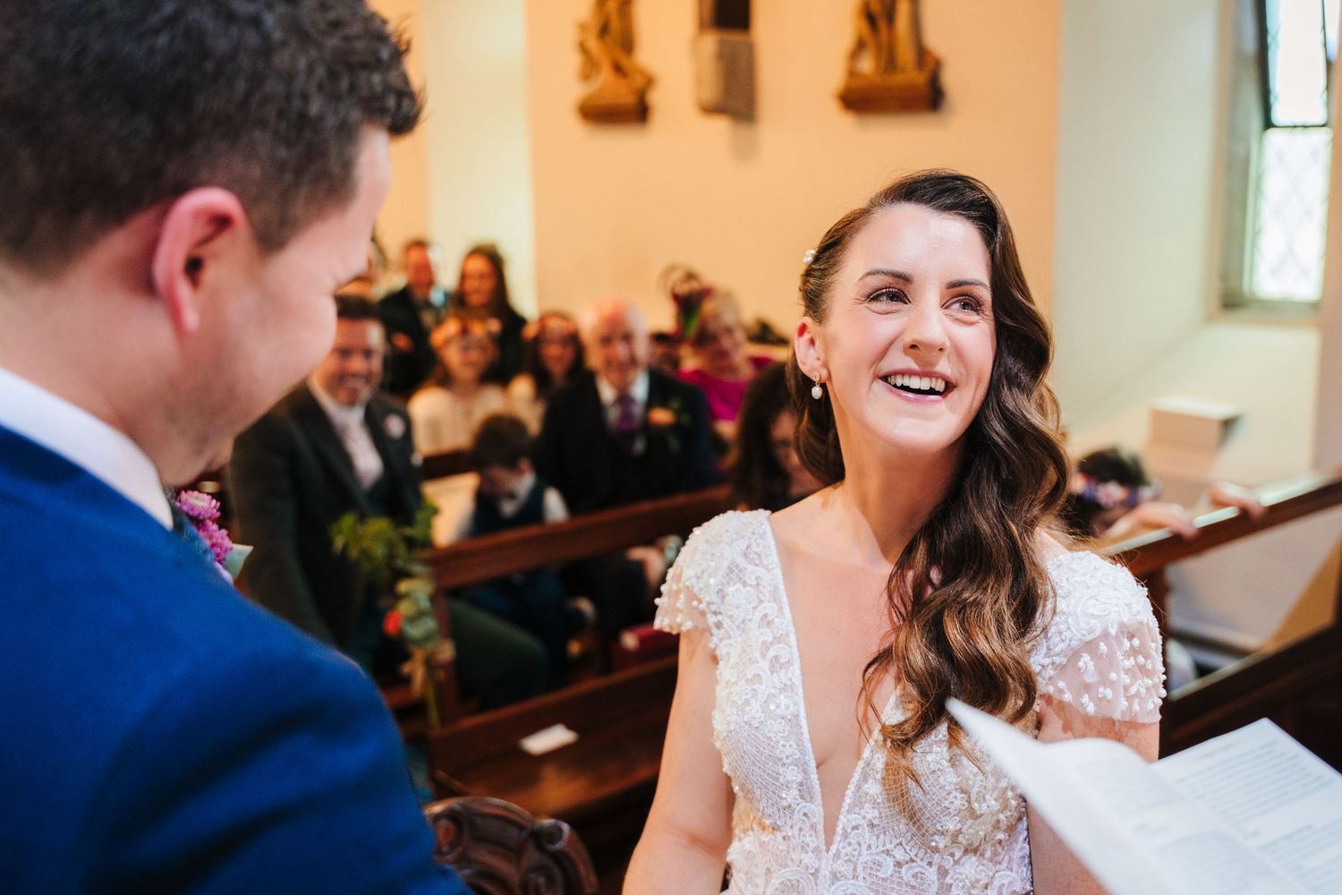 Wedding ceremony taking place in a traditional church with wooden pews and religious decor.