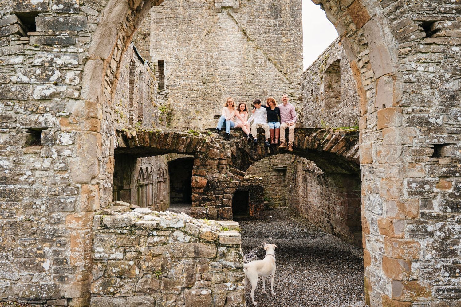 A series of stone archways and passageways in an ancient stone building or castle ruins. BEctive abbey family photographer dublin