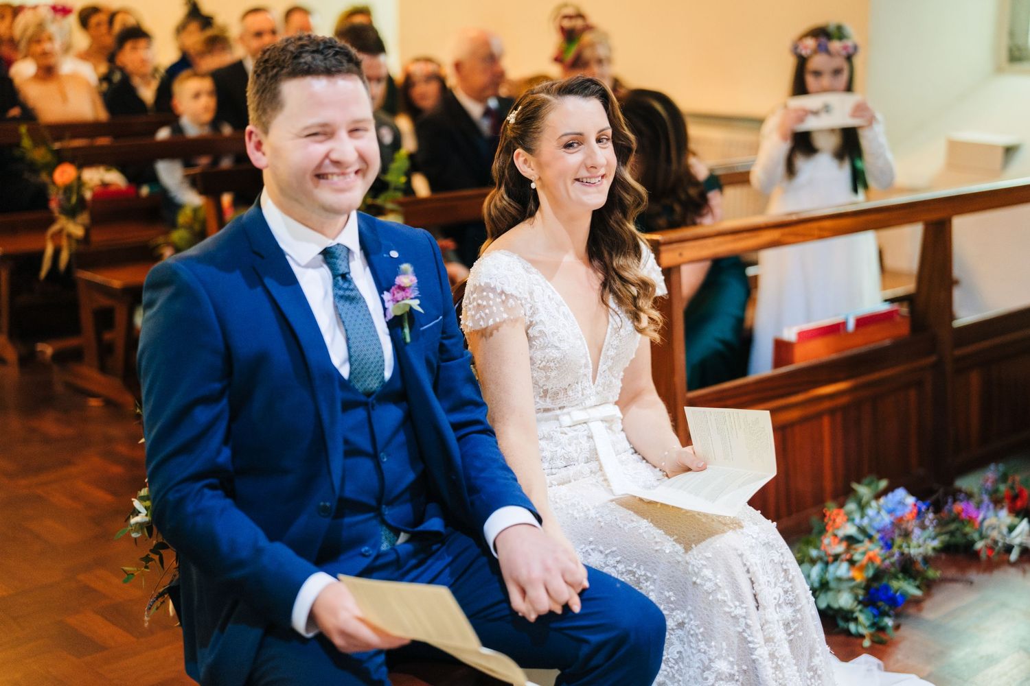 Wedding couple sitting together in a church pew during their ceremony.