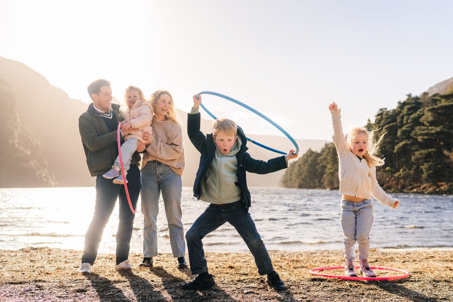 Family silhouettes walking together on a beach at sunset in a joyful candid moment. family PHOTOGRAPHER Dublin