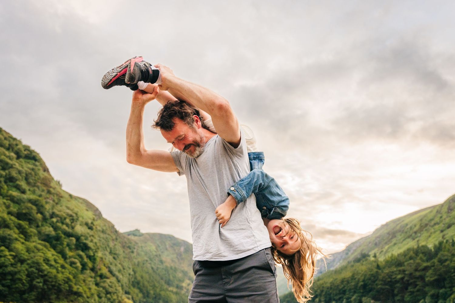 A carefree couple plays and laughs together while hiking in a scenic mountain valley during sunset. family PHOTOGRAPHER Dublin