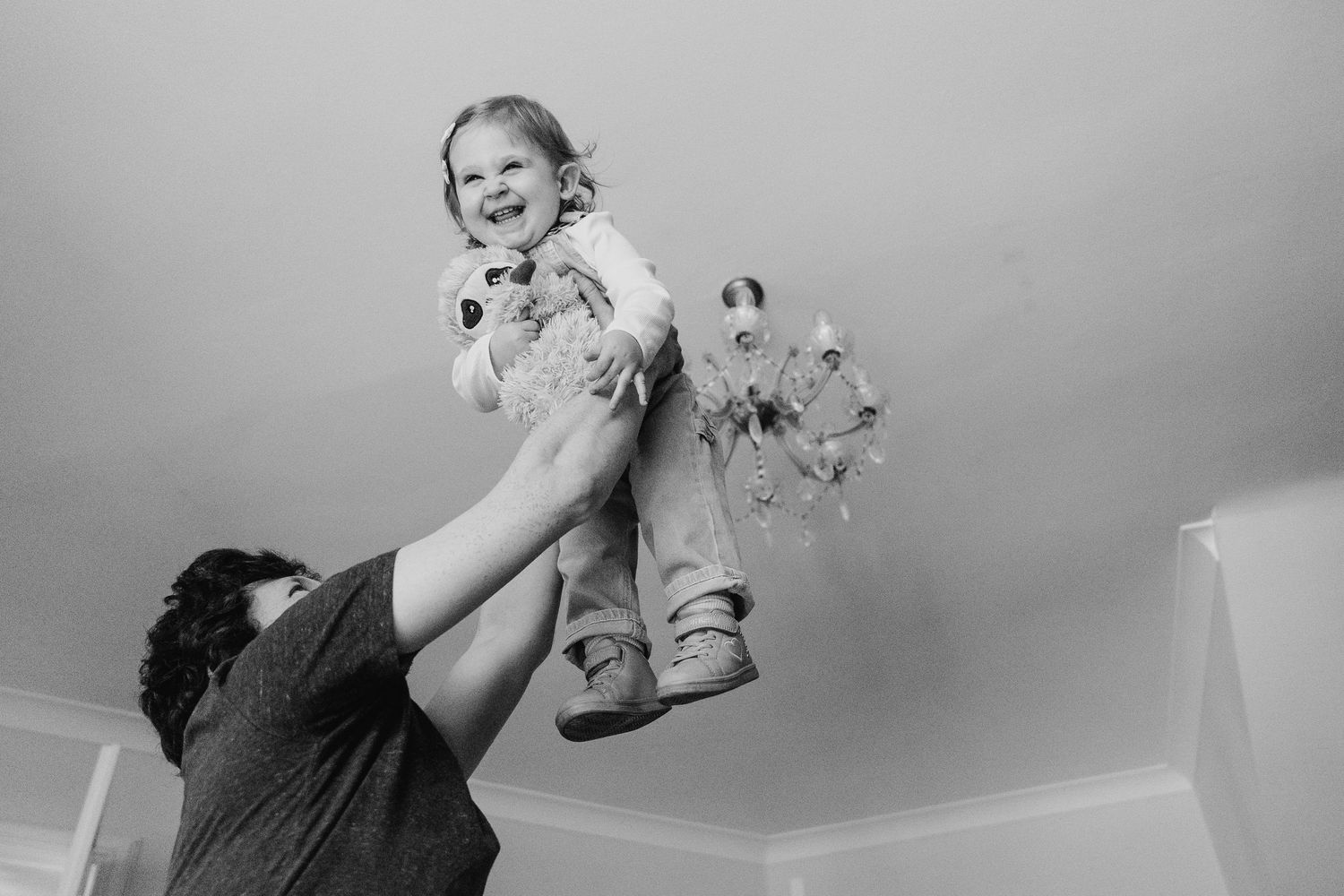 A black and white photo captures a joyful moment with someone being lifted high into the air by an adult figure. family PHOTOGRAPHER Dublin