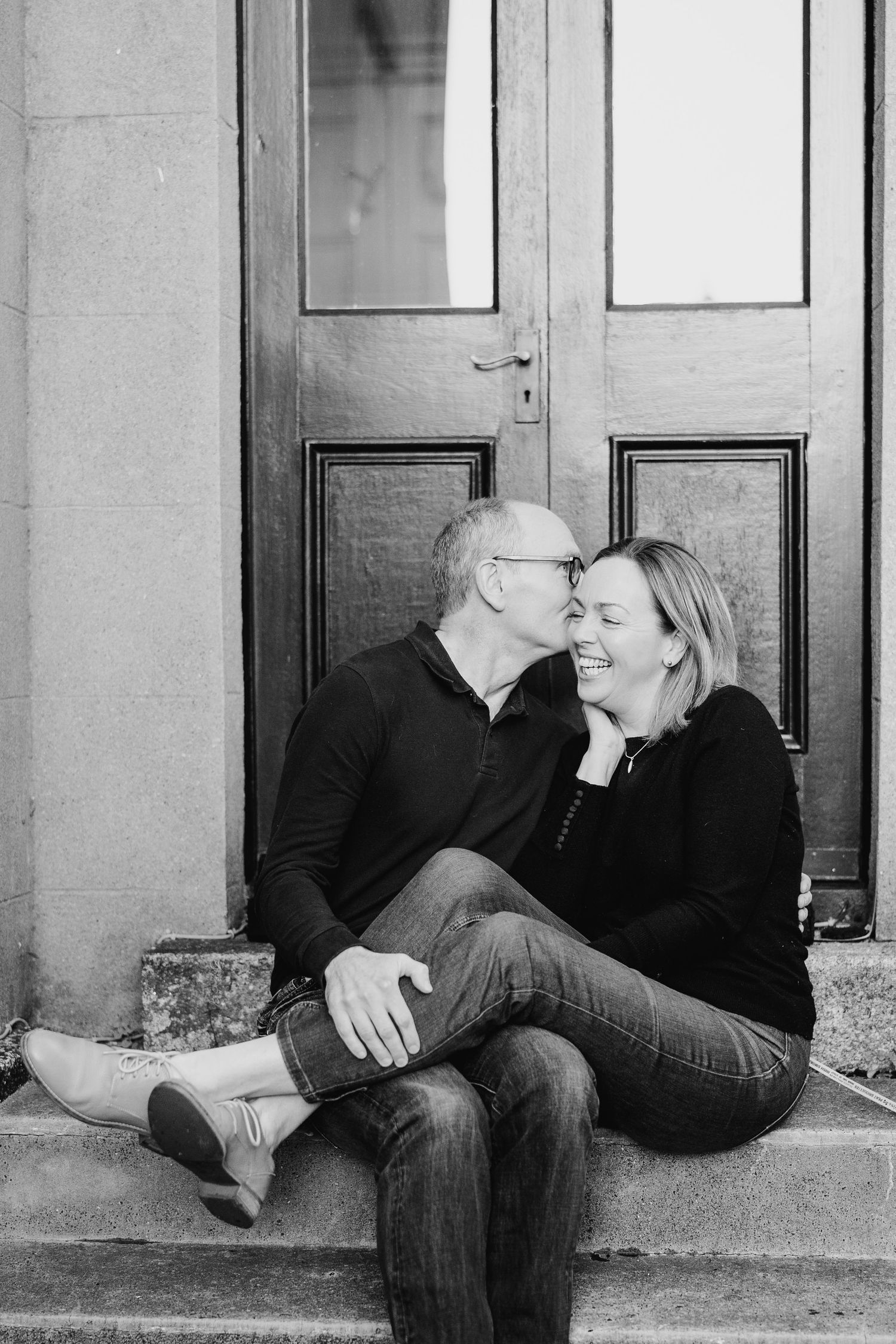 Sweet black and white portrait of a couple sharing an intimate moment while sitting together on outdoor steps. PHOTOGRAPHER Dublin ireland