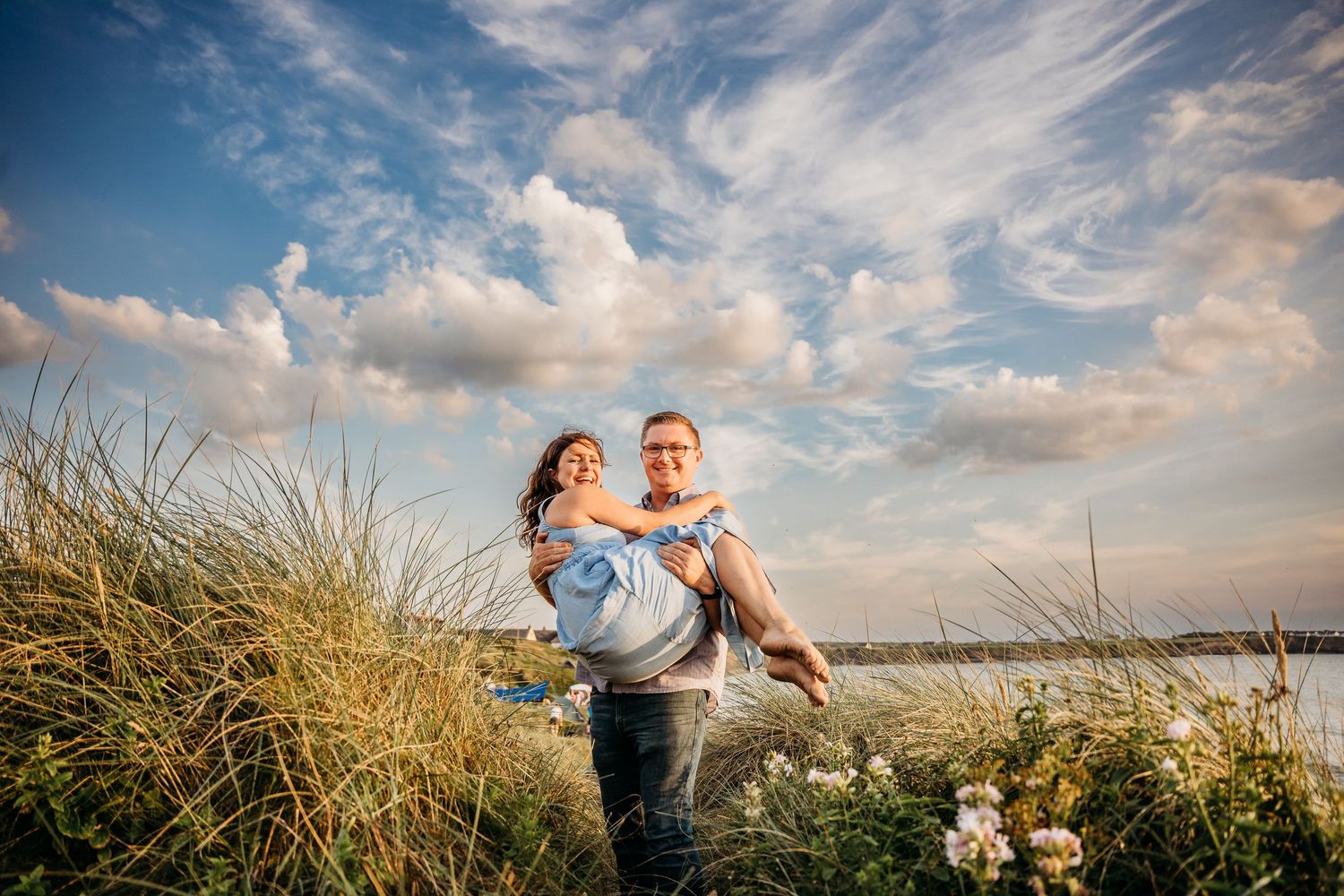 A romantic sunset portrait at a beach with tall grass and dramatic cloudy sky in the background. PHOTOGRAPHER Dublin ireland