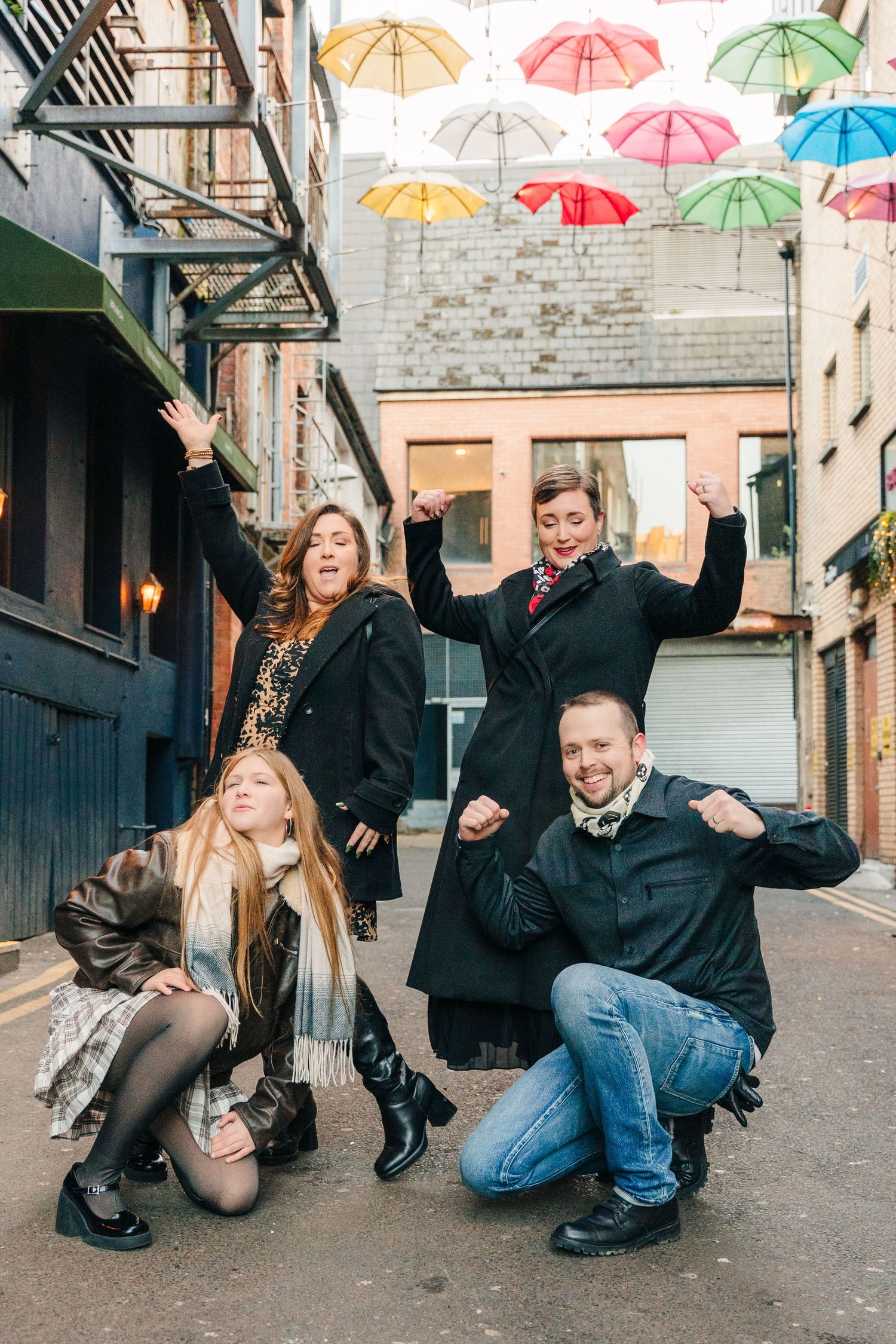 A creative photo sequence showing people dancing and posing with colorful umbrellas in an urban alley. family PHOTOGRAPHER Dublin