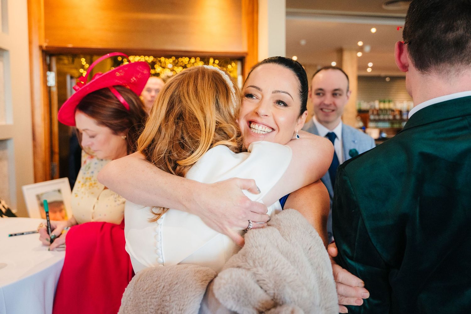 People embracing and celebrating during formal event in warmly lit venue.  Wedding PHOTOGRAPHER Trim Castle