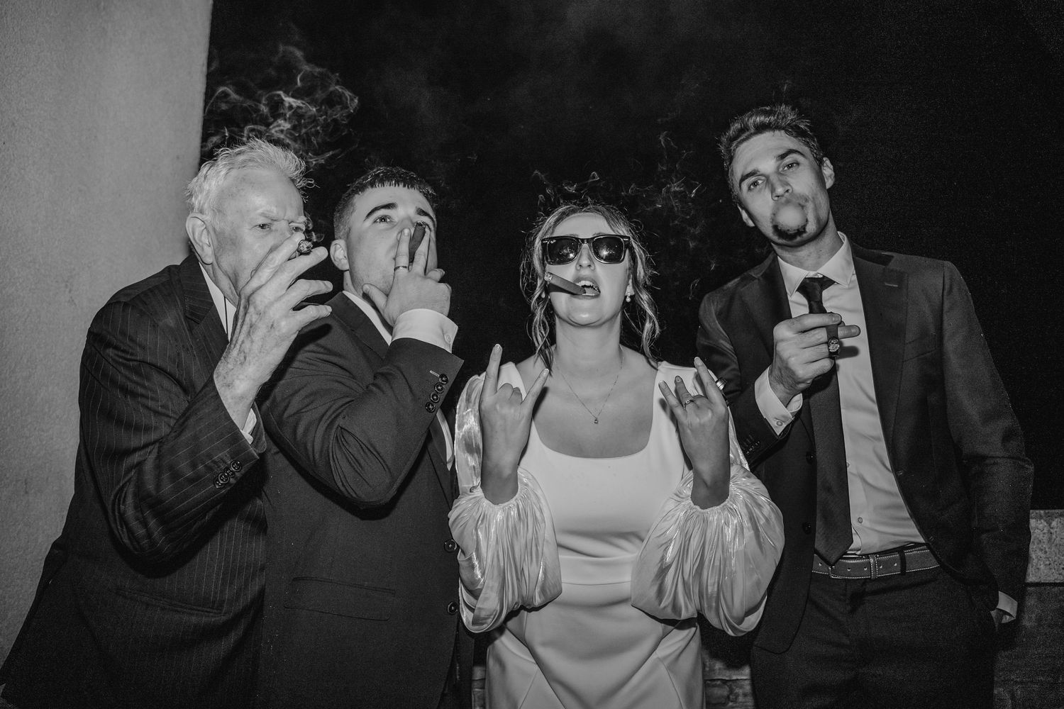 Black and white photo of wedding guests posing with drinks and sunglasses in playful style.Wedding Photography Trim Castle Ireland