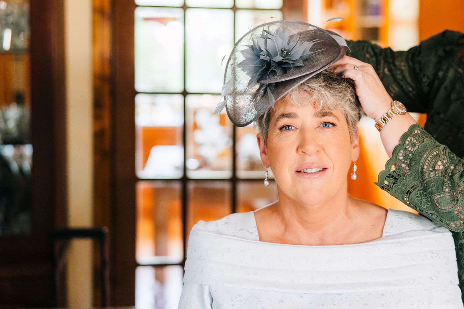 Millhouse slane wedding photographer dublinSomeone having their hair styled while wearing an elegant gray headpiece and formal attire.