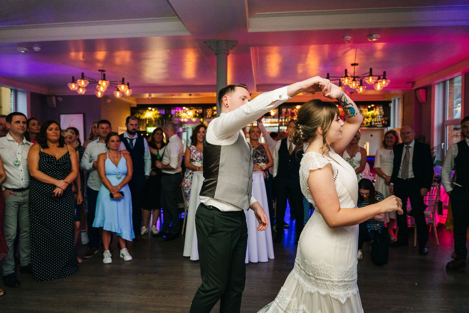 Couple performs romantic dance moves while guests watch during wedding reception with ambient lighting. PHOTOGRAPHER Dublin Ireland Wedding