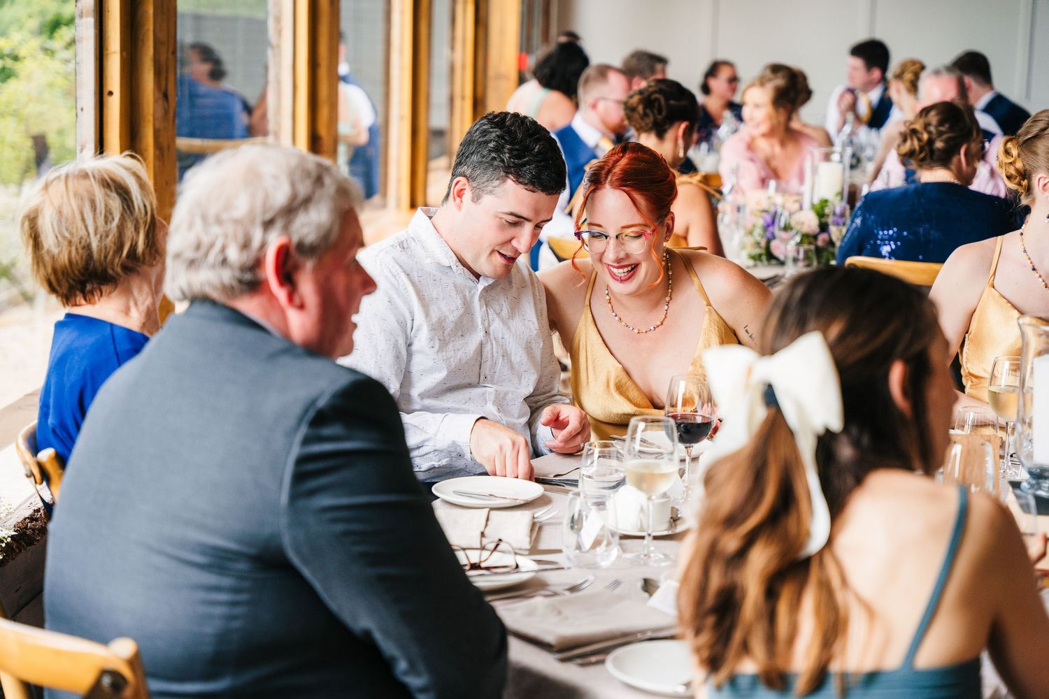 Poulaphouca Wedding photographer wicklow  Wedding guests seated at long tables during an indoor reception with natural lighting.