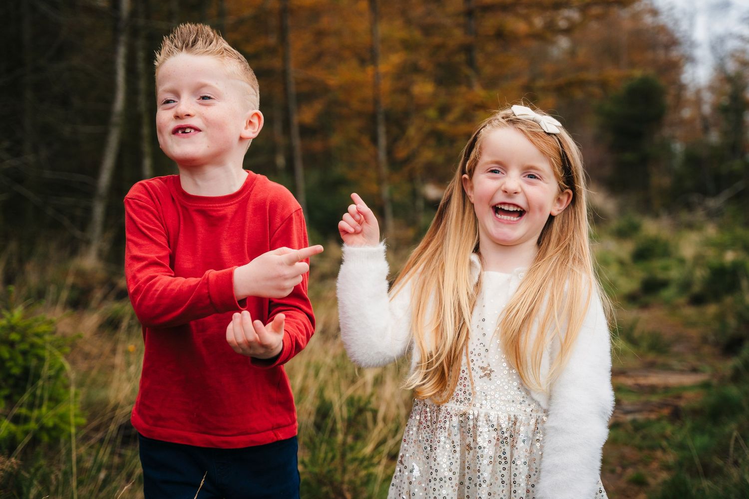 Family Photographer Dublin Ireland Candid family moment captured against autumnal trees with red and white clothing.