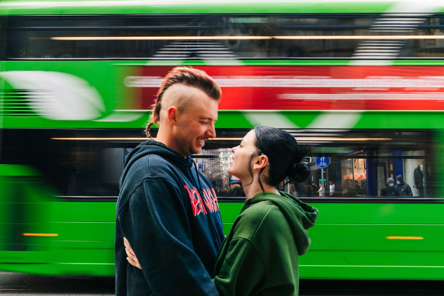 A couple embraces on a Dublin street as a bright green bus streaks past in motion blur. PHOTOGRAPHER Dublin Ireland
