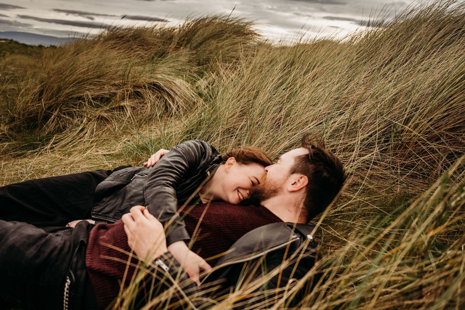 A series of dramatic photographs showing figures lying among windswept beach grass on sand dunes. engagement PHOTOGRAPHER Dublin