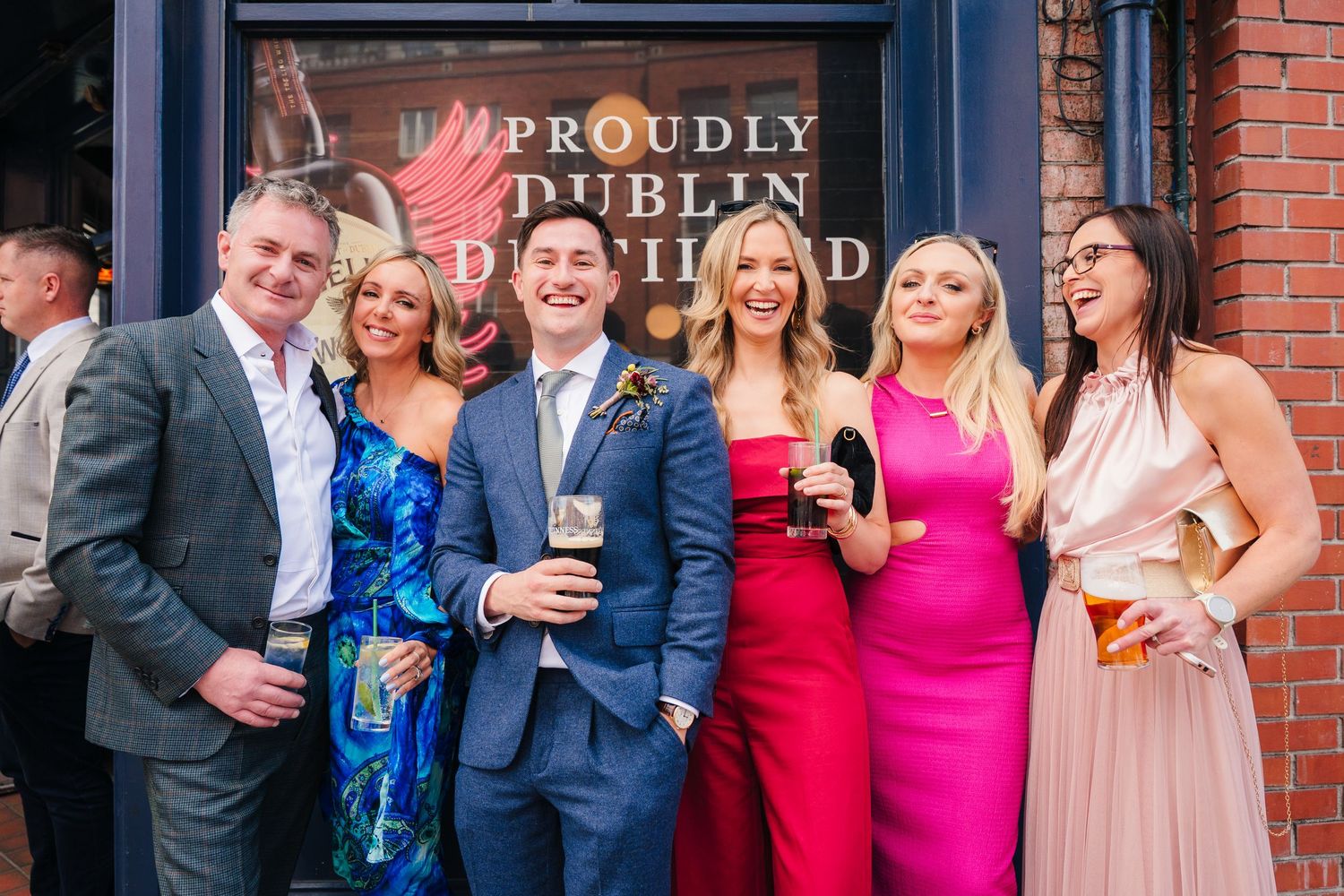 Wedding celebration group laughing together outside brick building. Same sex wedding PHOTOGRAPHER Dublin