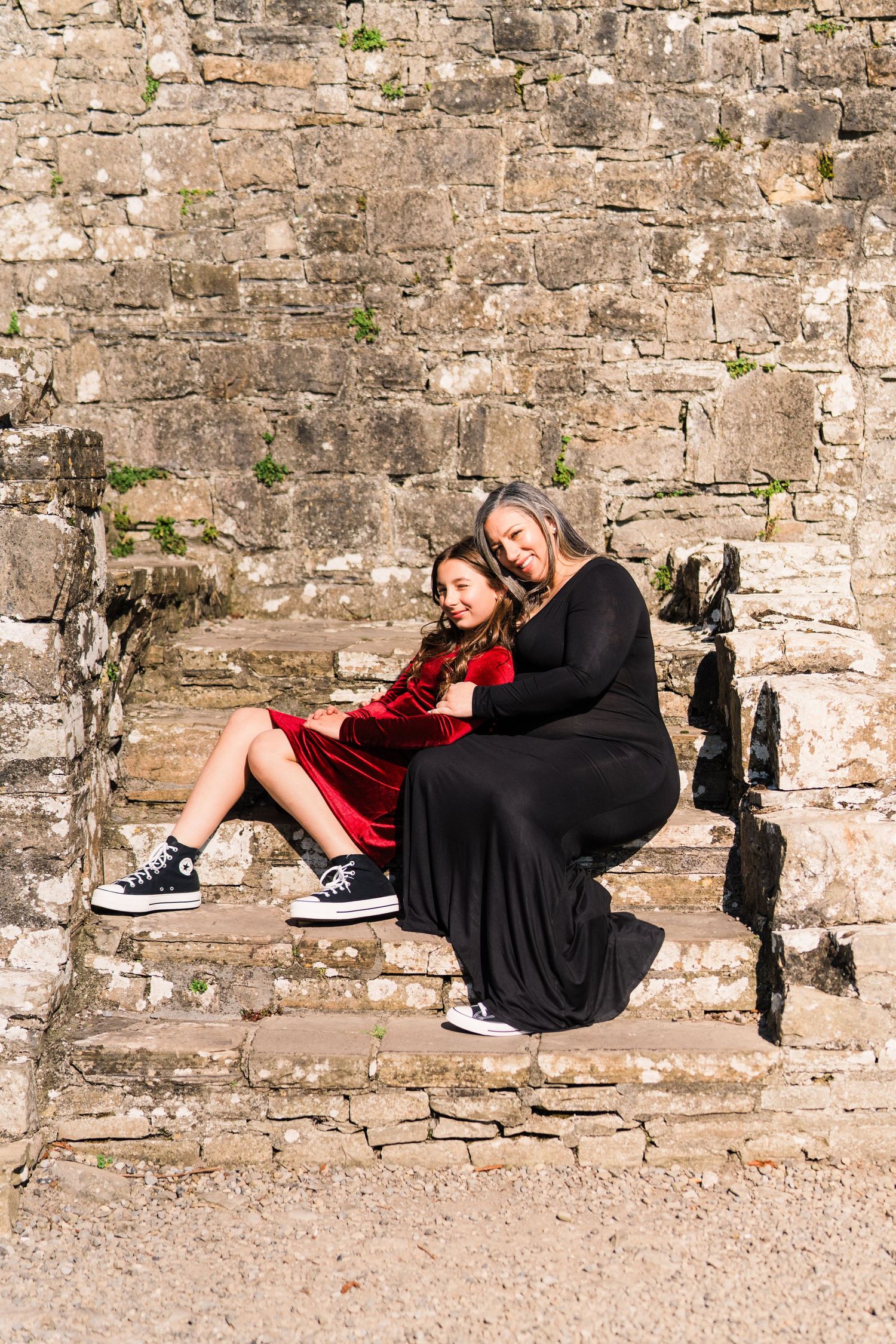 Artistic sequence showing a person in black dress relaxing against an old stone wall. Family PHOTOGRAPHER Dublin