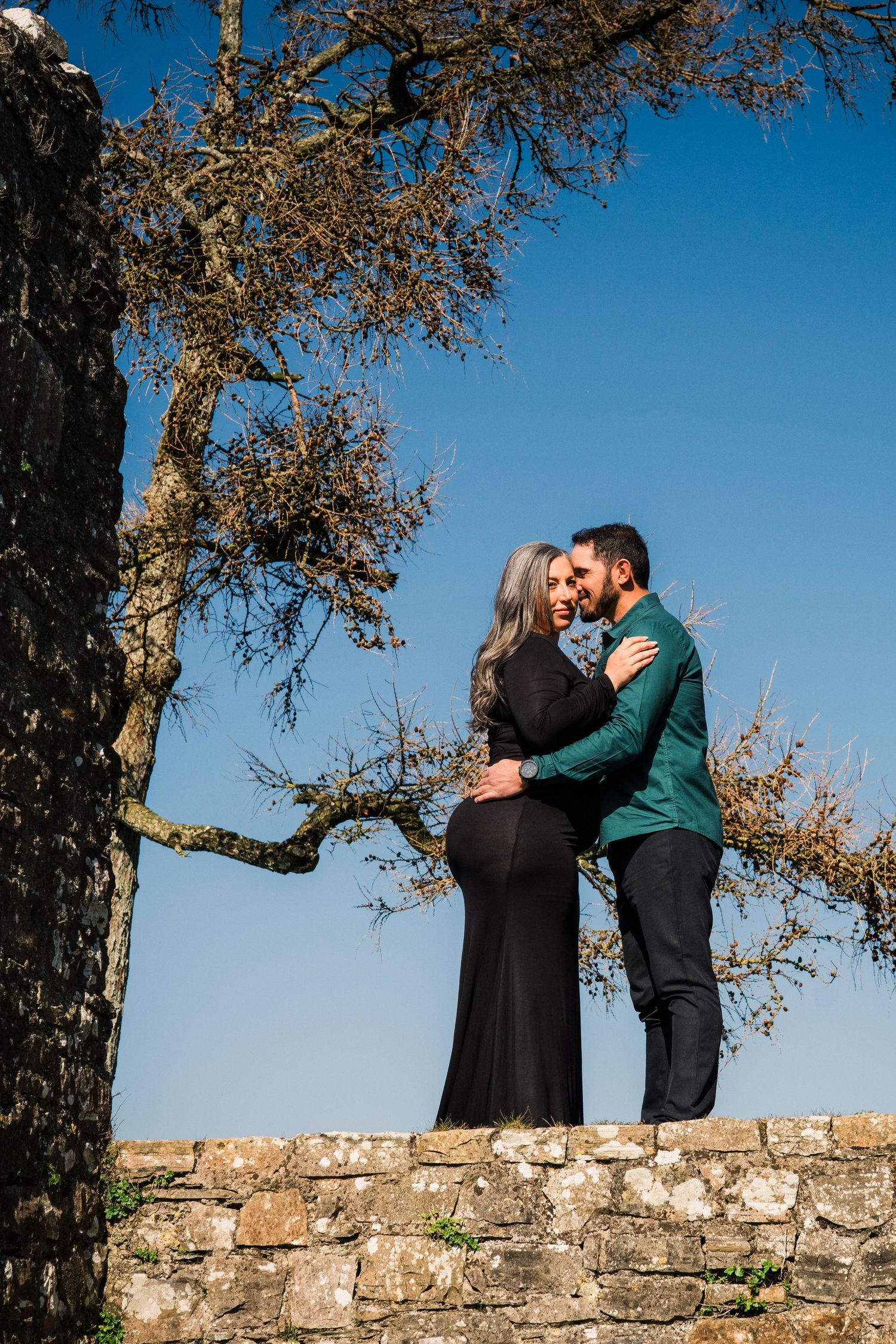 Romantic sequence on stone castle walls with autumn trees and blue sky background. Family PHOTOGRAPHER Dublin