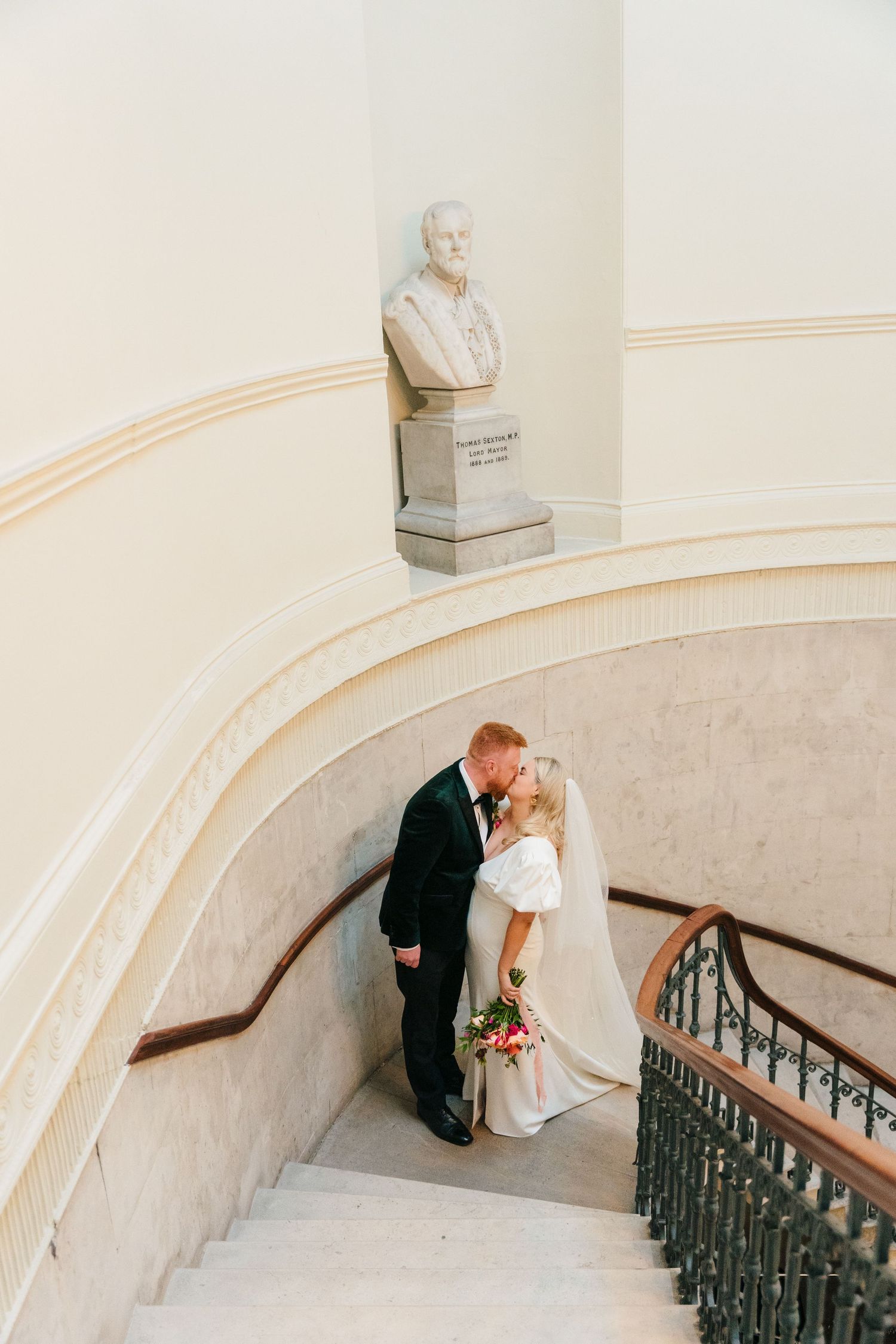 Wedding couple poses on curved marble staircase with classic architectural details. Wedding photographer dublin