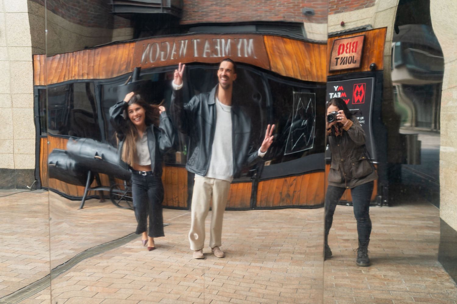 A group of people walk past closed storefronts and shuttered businesses along a dark urban alleyway or passage. Couple's Photoshoot PHOTOGRA