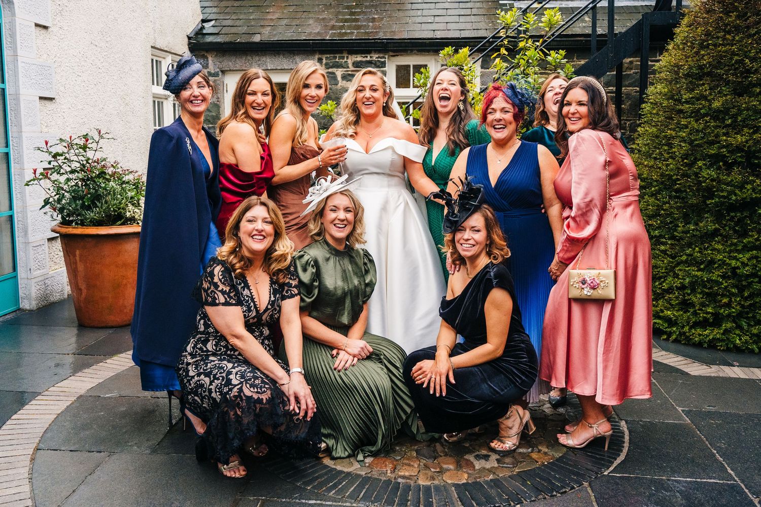 Bridal party in mix of colorful dresses poses together on stone patio.  Virginia Park Lodge Wedding Photographer Cavan Dublin Ireland