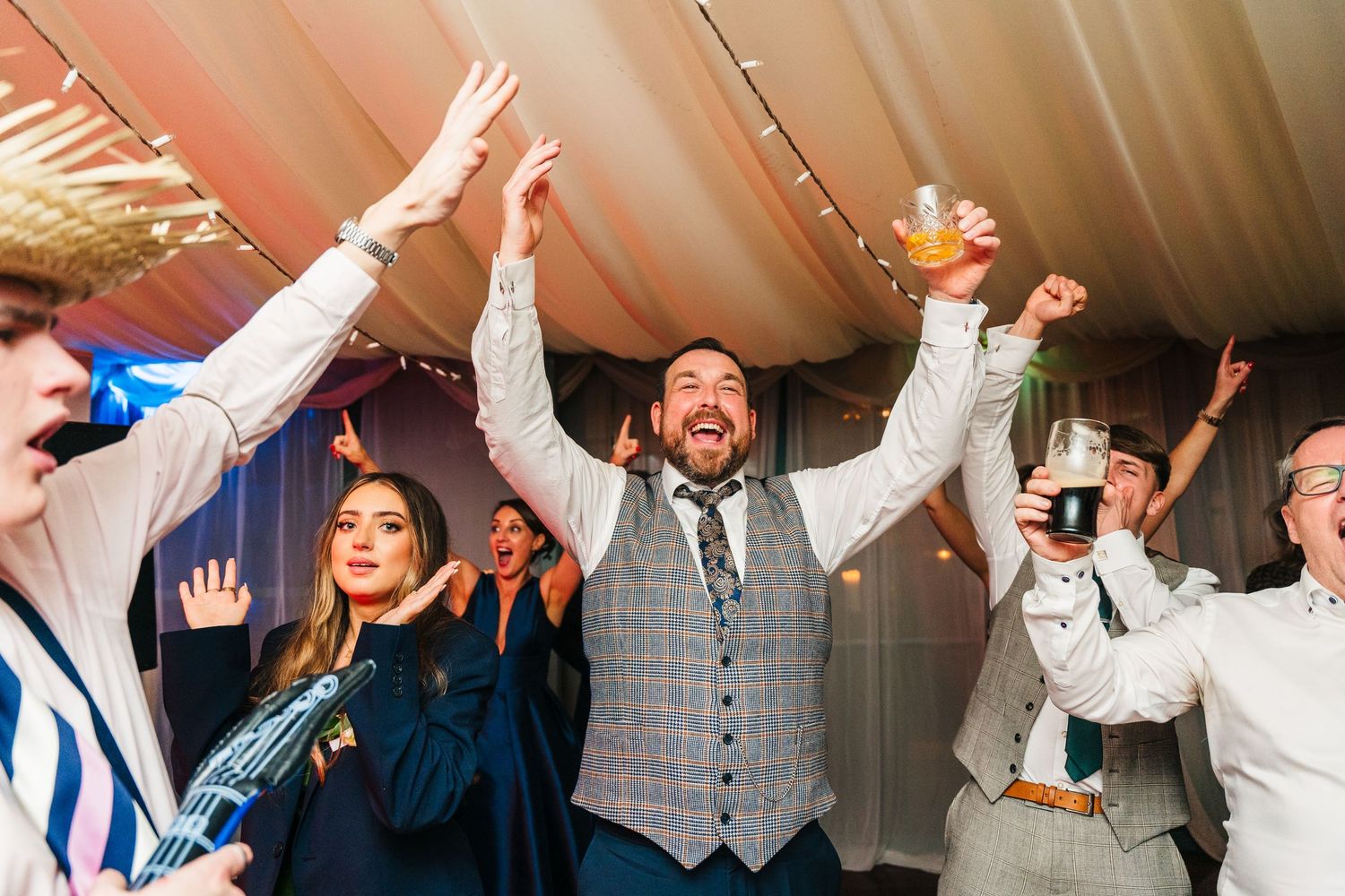 Energetic wedding reception dance party with guests celebrating under string lights in a tent venue.  Virginia Park Lodge Wedding Photograph