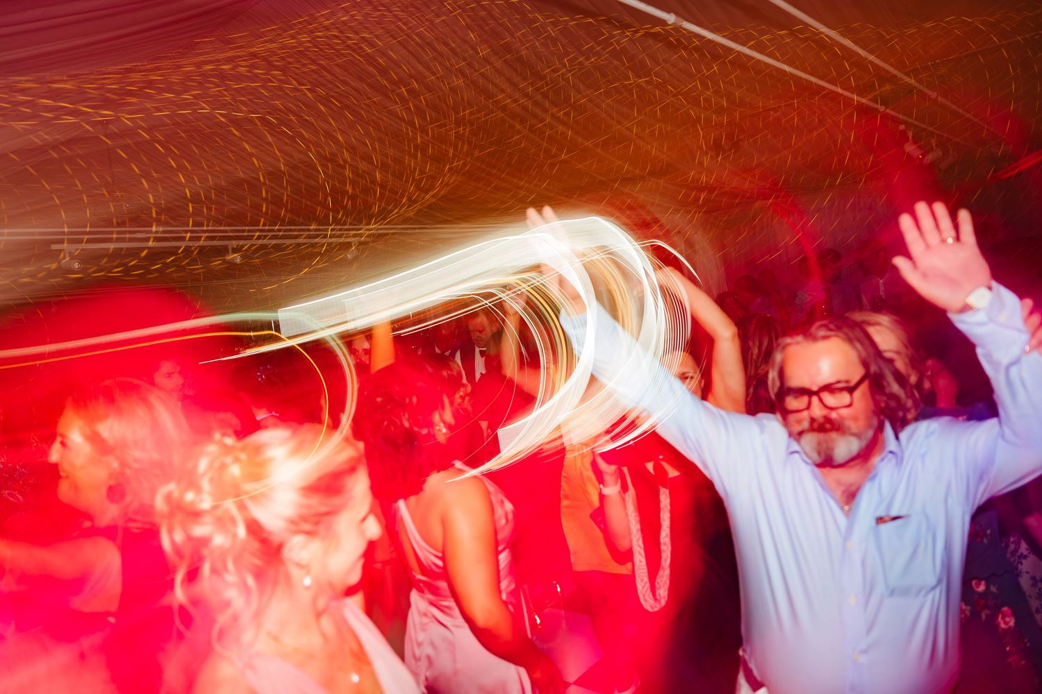 Wedding party dancing under red mood lighting at an evening reception celebration. LGBTQ Ashley Park Wedding Photographer