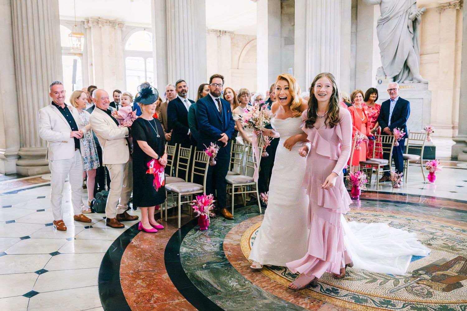 Wedding celebration in a grand columned hall with guests watching as couple dances on marble floor.  city hall dublin wedding photos