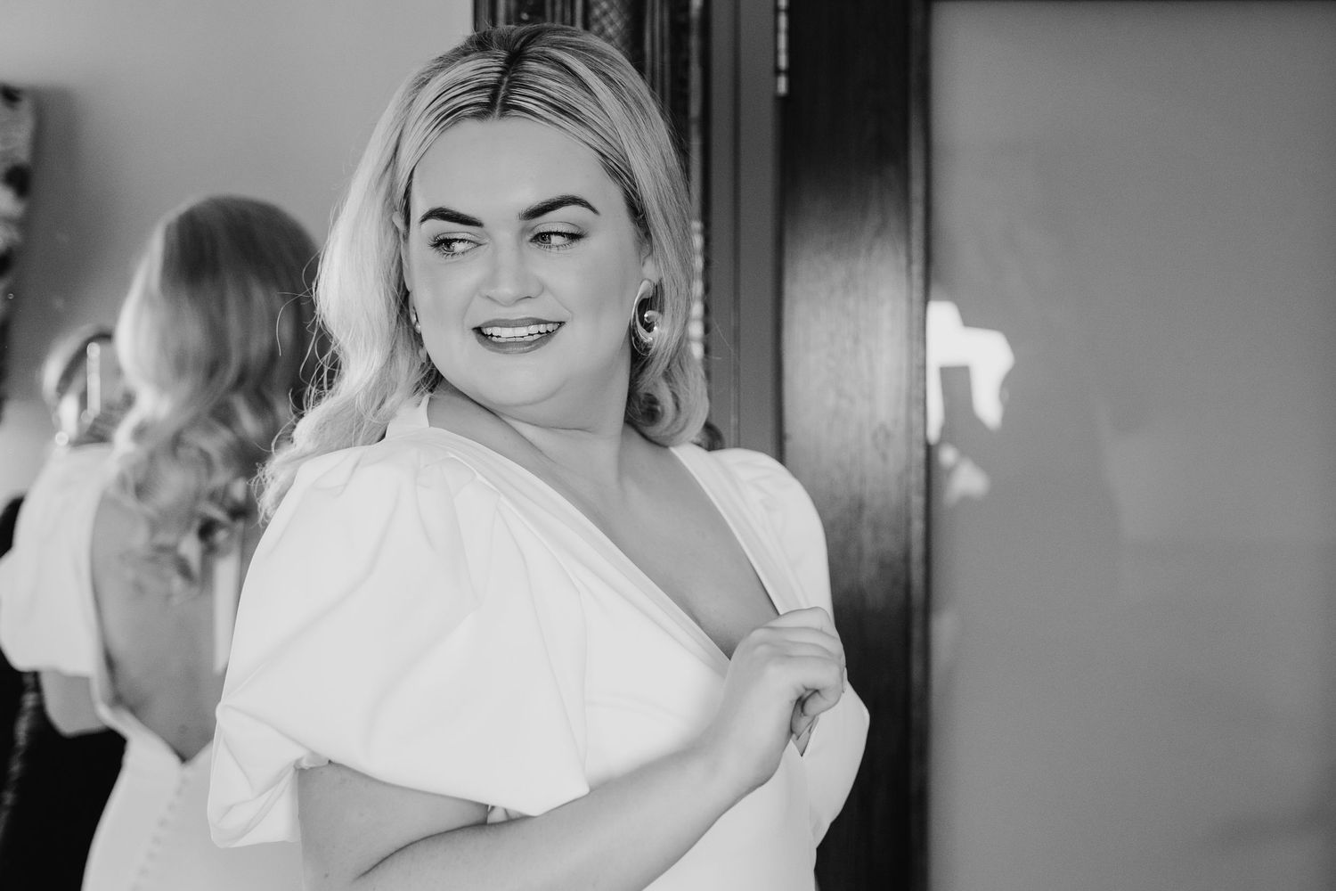 A person in a white one-shoulder dress poses elegantly against a dark background. Wedding photographer dublin