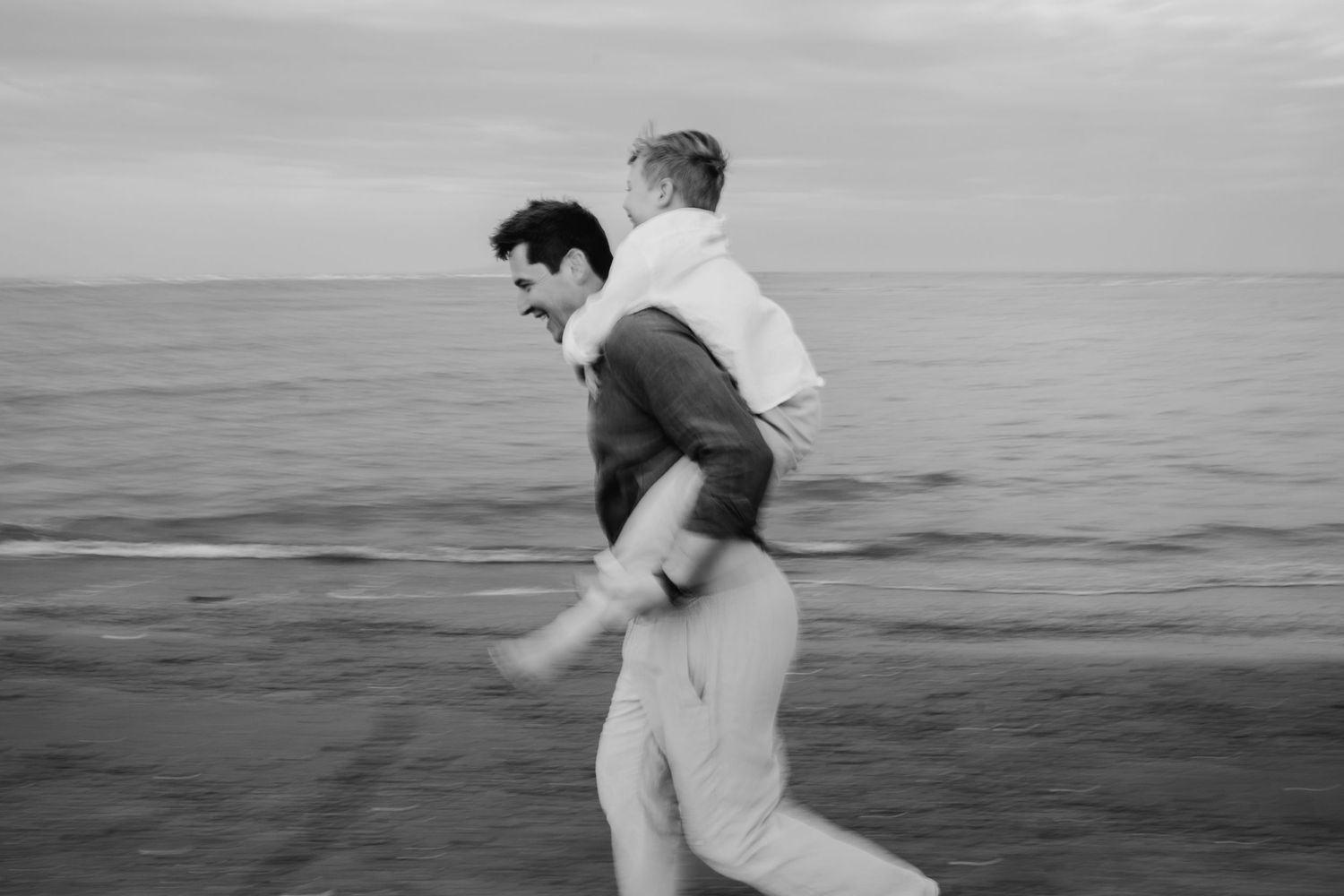 A sequence of black and white photos shows people joyfully running and splashing at the edge of the ocean. family PHOTOGRAPHER Dublin
