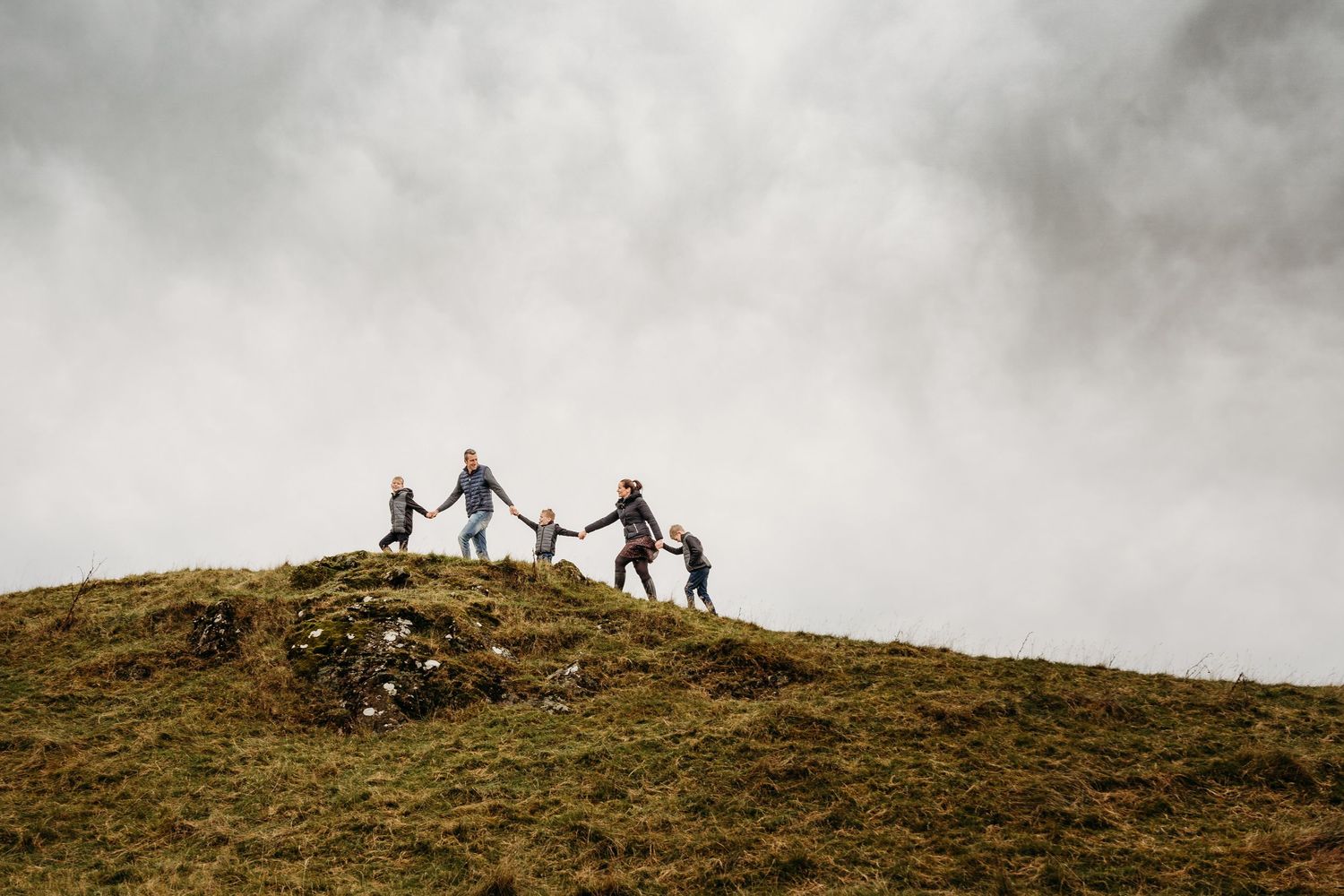 Silhouetted hikers traverse a rugged mountain ridge against a misty overcast sky in dramatic landscape scenery. family PHOTOGRAPHER Dublin