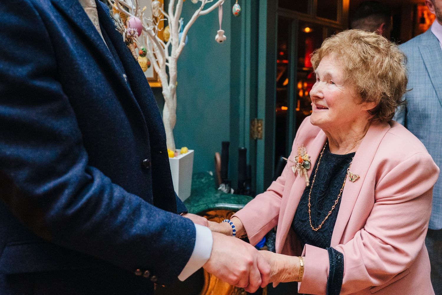 Wedding guests share cheerful moments in a cozy venue with teal-colored walls. Marco Pierre Dublin Wedding Photographer